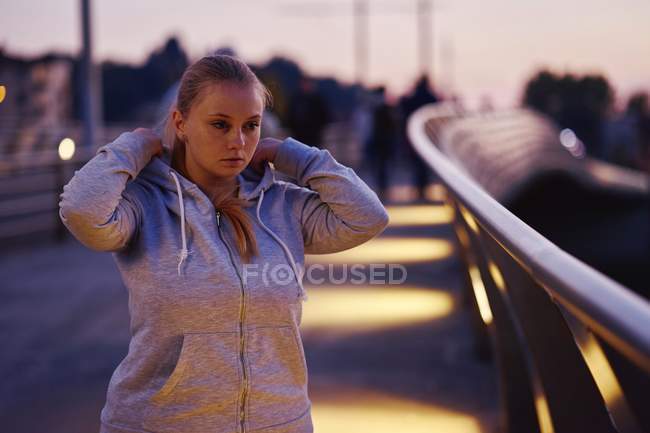 Kurvige junge Frau trainiert in der Abenddämmerung auf Fußgängerbrücke — Stockfoto