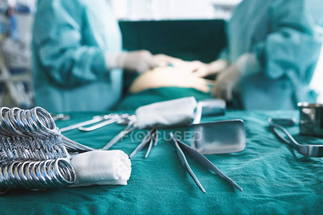Close up of surgical instruments with surgeons performing surgery in maternity ward operating theatre — Stock Photo
