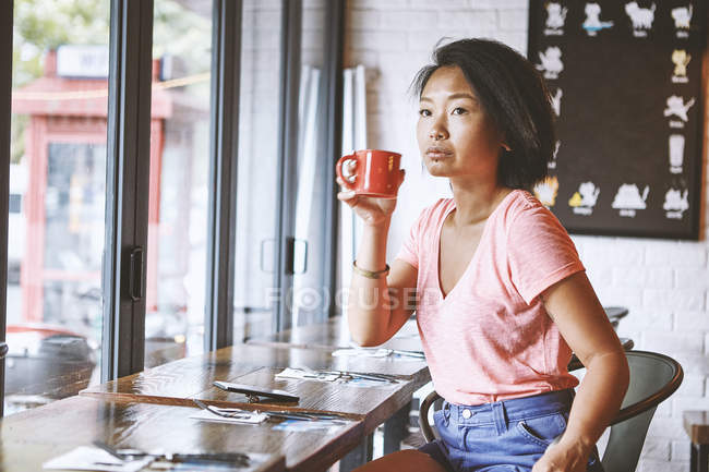 Femme dans un café regardant depuis le siège de la fenêtre, concession française de Shanghai, Shanghai, Chine — Photo de stock