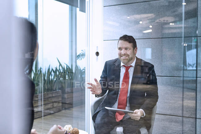 View through glass wall of colleagues having meeting in office — Stock Photo