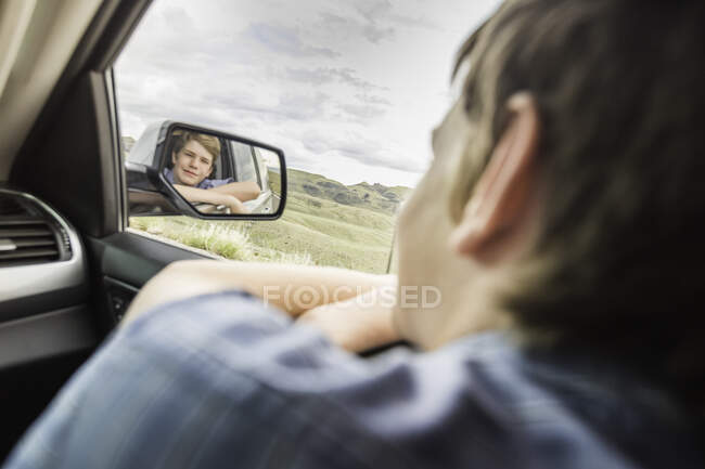 Rapaz em viagem de carro inclinado para fora da janela do carro — Fotografia de Stock