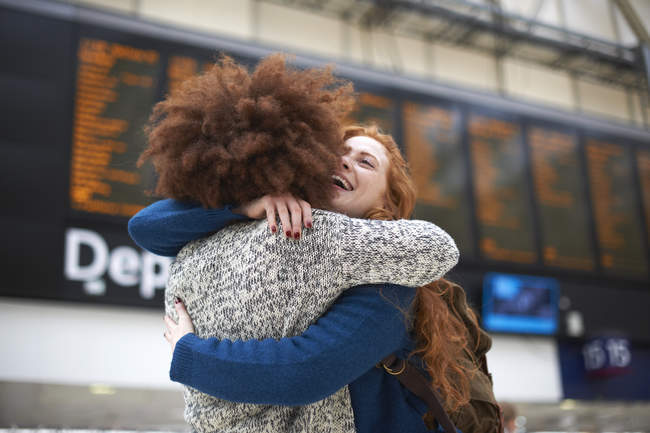 Two young women hugging at train station — Stock Photo