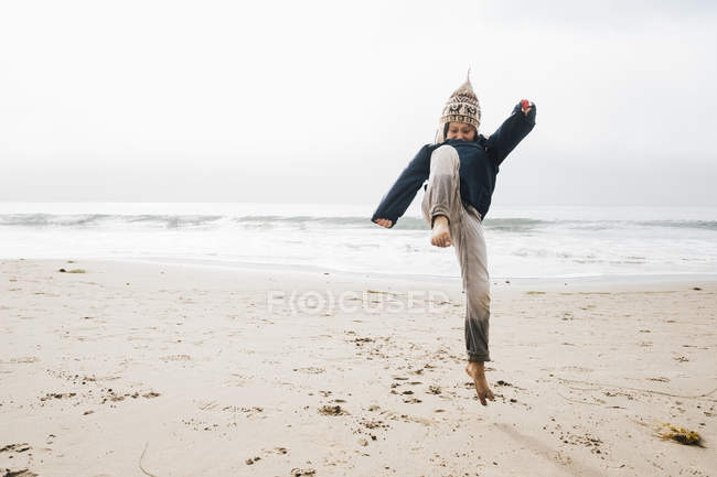 Young boy on beach jumping mid air — Stock Photo