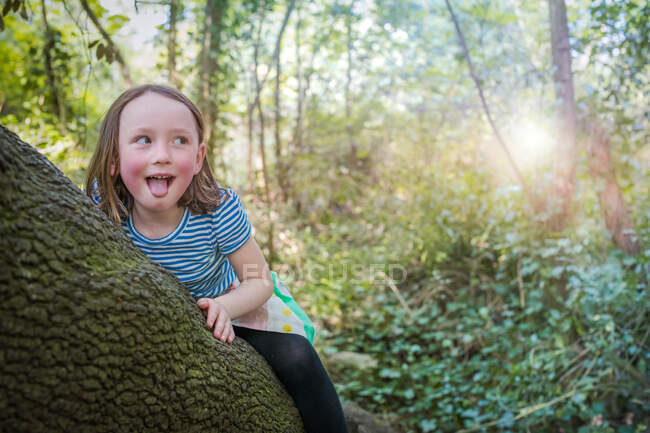Mischievous girl on tree trunk — Stock Photo