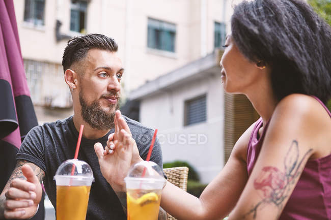 Многонациональная пара хипстеров разговаривает в кафе на тротуаре, Шанхайская французская концессия, Шанхай, Китай — стоковое фото