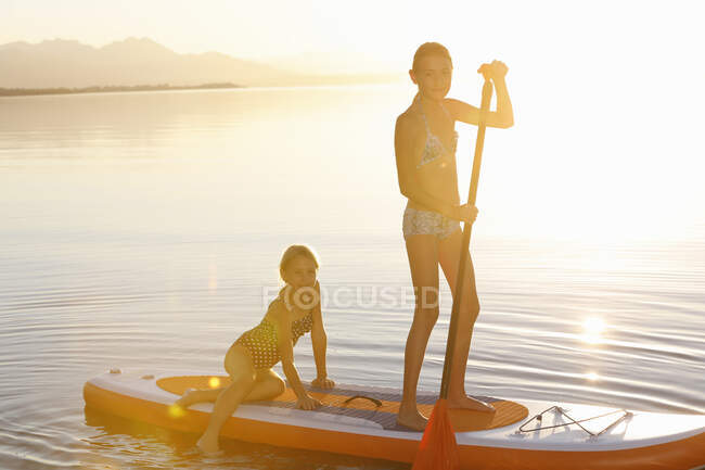 Two young girls paddle boarding on water — Stock Photo
