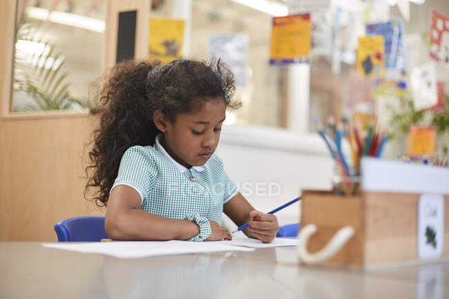 Школярка пише в класі на робочому столі в початковій школі — стокове фото