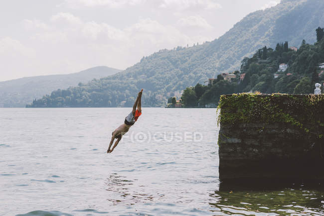 Jovem nadador do sexo masculino mergulho no cais, Lago de Como, Lombardia, Itália — Fotografia de Stock