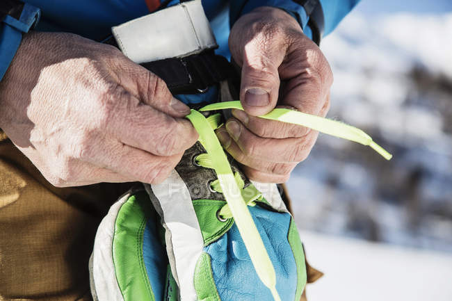 Close up of skier tying laces on ski gloves — Stock Photo