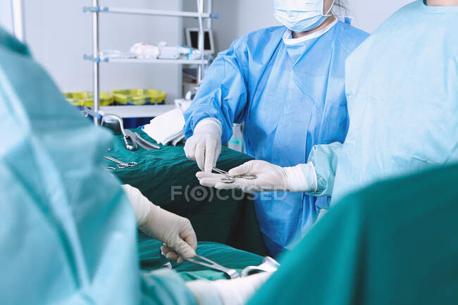 Sobre a visão do ombro do cirurgião entregou tesoura cirúrgica na maternidade sala de operações — Fotografia de Stock