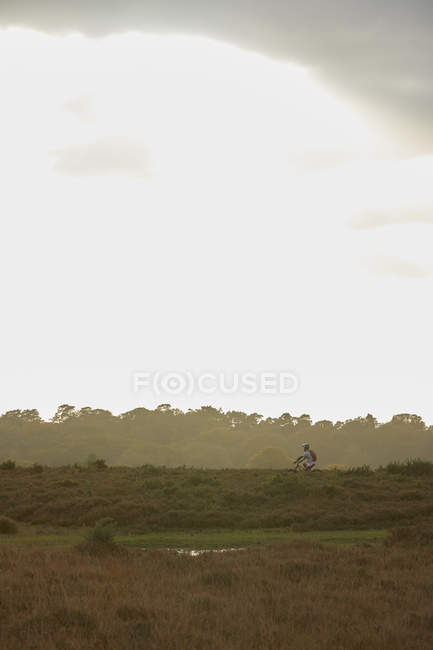 Fernsicht eines männlichen Mountainbikers, der über Moor fährt — Stockfoto