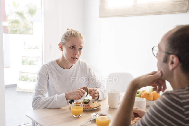 Jovem mulher e namorado conversando na mesa de café da manhã — Fotografia de Stock