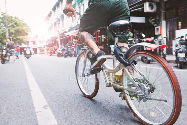 Waist down of young male hipster cycling along city street, Shanghai French Concession, Shanghai, China — Stock Photo
