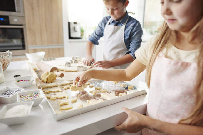 Девочка и брат пекут пасхальное печенье на кухне — стоковое фото