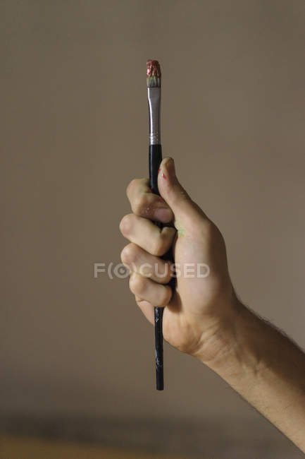 Close up of male artist holding paintbrush in hand — Stock Photo