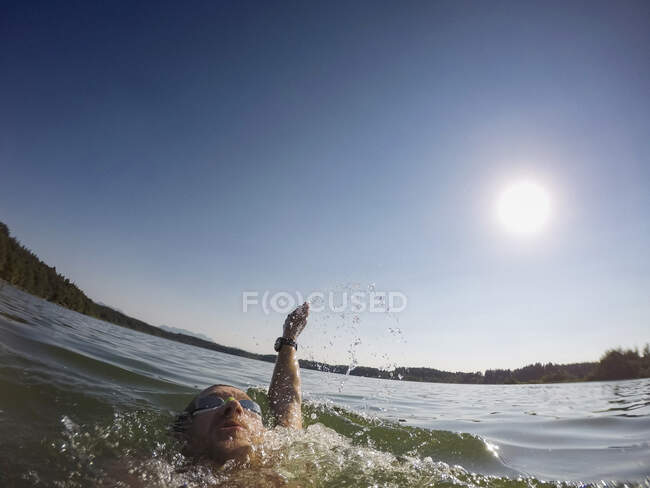 Зрілий чоловік плаває на фоні озера, крупним планом — стокове фото