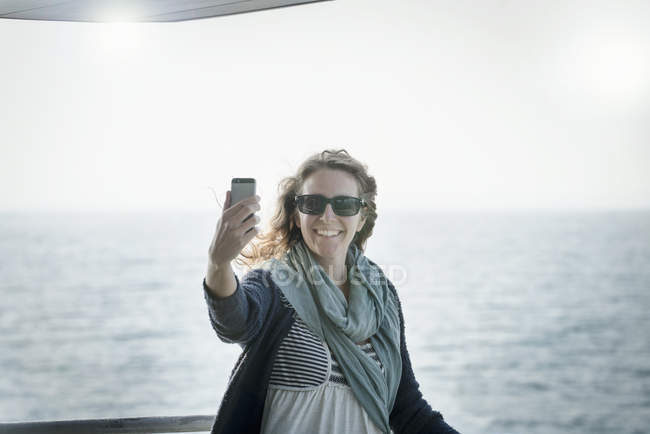 Woman in sunglasses taking selfie with sea at background — Stock Photo