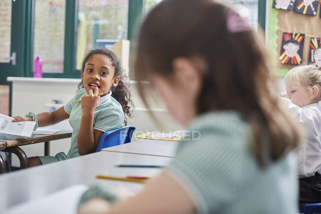 Estudante olhando por cima de seu ombro na sala de aula na escola primária — Fotografia de Stock