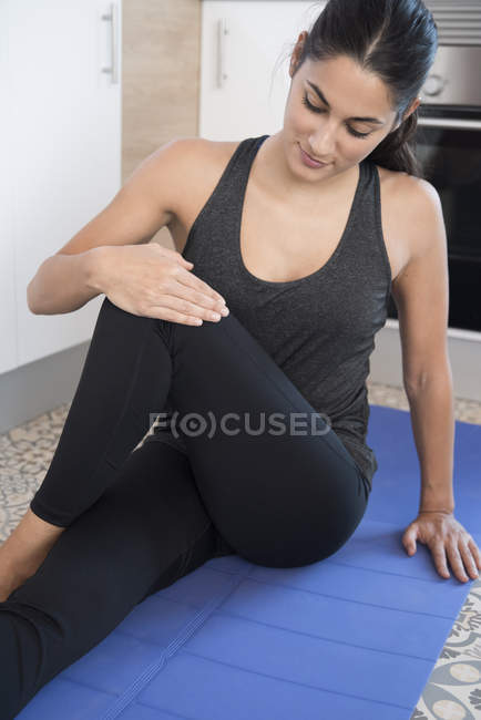Жінка робить вправи на килимку на підлозі кухні — стокове фото