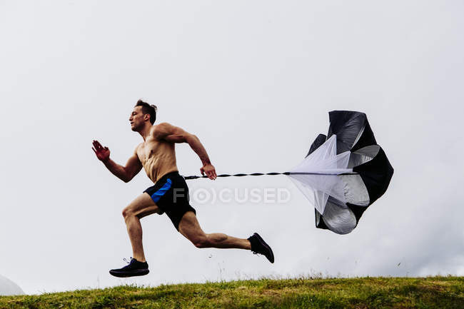 Homem correndo e treinando com paraquedas — Fotografia de Stock