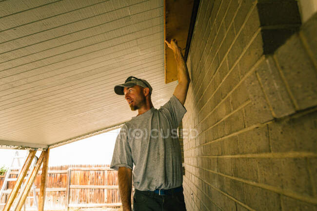 Elettricista regge trave di legno in portico — Foto stock