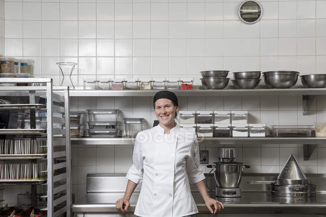 Портрет шеф-кухаря на комерційній кухні, дивлячись на камеру посміхаючись — стокове фото