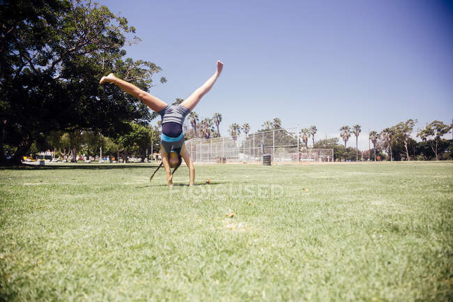 Schoolgirl doing cartwheel on school sports field — Stock Photo