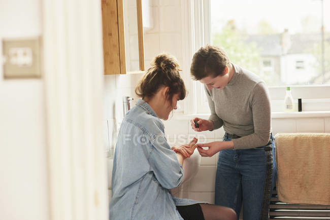 Amigos aplicando verniz de unhas no banheiro — Fotografia de Stock