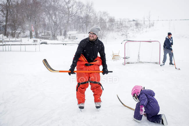 Father and daughter playing ice hockey in winter landscape — Stock Photo