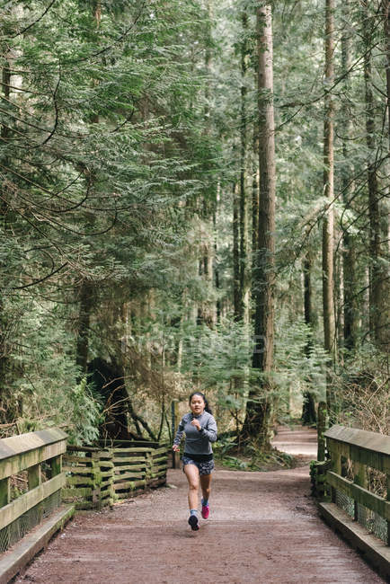 Mujer corriendo en el bosque, Vancouver, Canadá - foto de stock