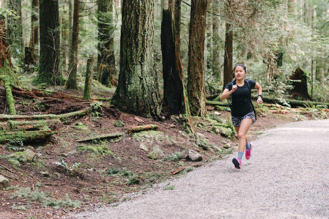 Mujer corriendo en el bosque, Vancouver, Canadá - foto de stock