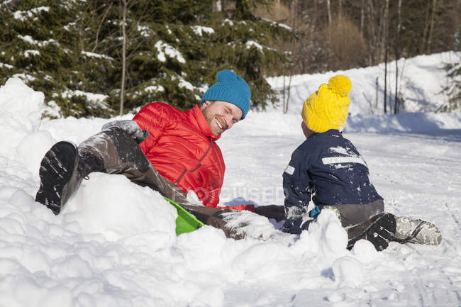 Чоловік і син сміються після падіння з болотого в снігу — стокове фото