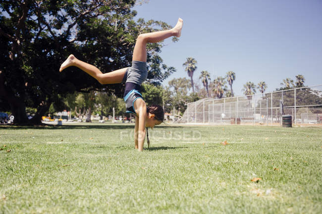 Estudante fazendo cartwheel no campo de esportes da escola — Fotografia de Stock