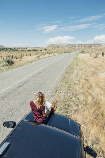 Mulher sentada no carro e olhando para o mapa — Fotografia de Stock