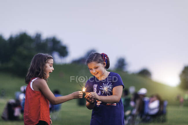 Meninas segurando sparklers sorrindo — Fotografia de Stock