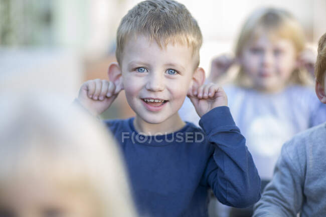 Portrait of young boy, outdoors, holding eats, smiling — Stock Photo