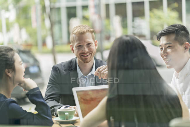 Grupo de gente de negocios se reúnen en la cafetería y el uso de ordenador portátil - foto de stock