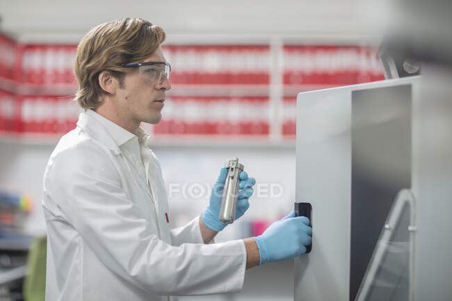 Male worker in thread factory, placing lab samples in chemical oven — Stock Photo