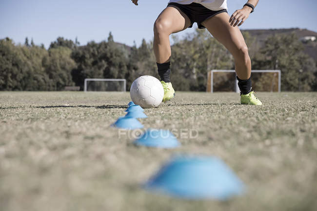 Cropped view of sportswoman playing football with ball — Stock Photo