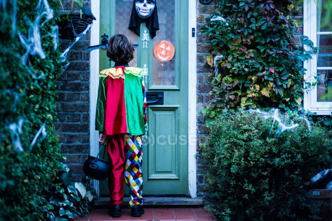 Kleiner Junge im Halloween-Kostüm, der vor der Tür steht, trickst oder behandelt, Rückansicht — Stockfoto