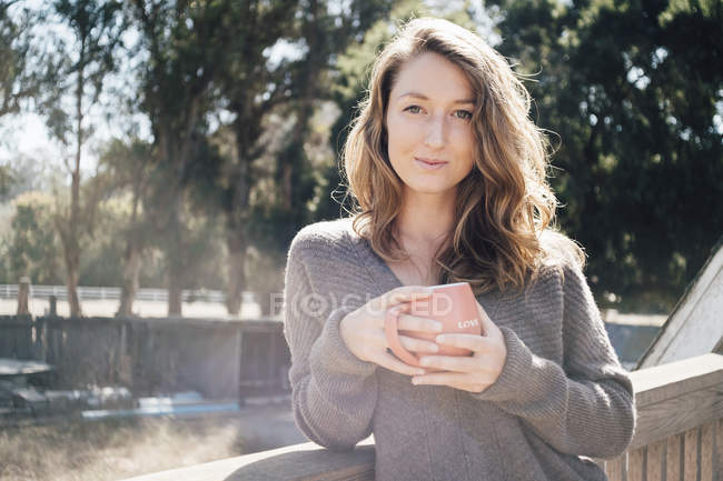 Portrait de jeune femme en plein air tenant tasse de café — Photo de stock