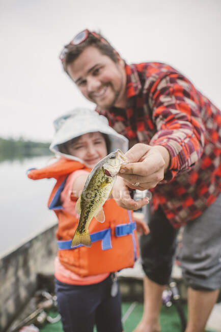 Pai e filha em barco no lago, pai mostrando filha peixe capturado — Fotografia de Stock