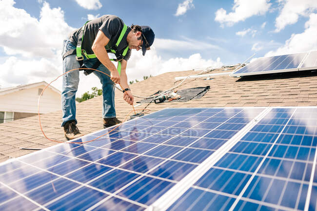 Рабочий, устанавливающий солнечные панели на крыше дома — стоковое фото