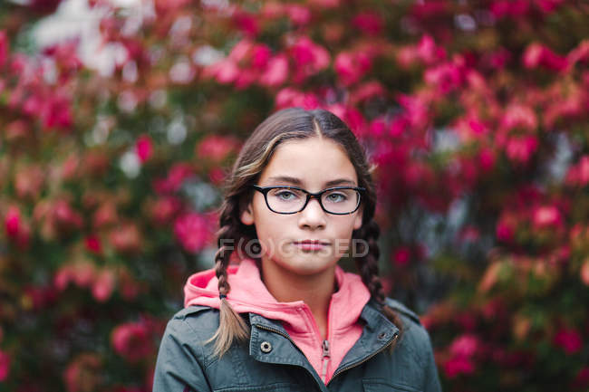 Портрет дівчини з пелюстками і окулярами дивиться на камеру — стокове фото