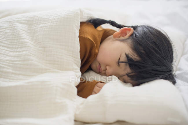 Маленькая девочка спит в постели — стоковое фото