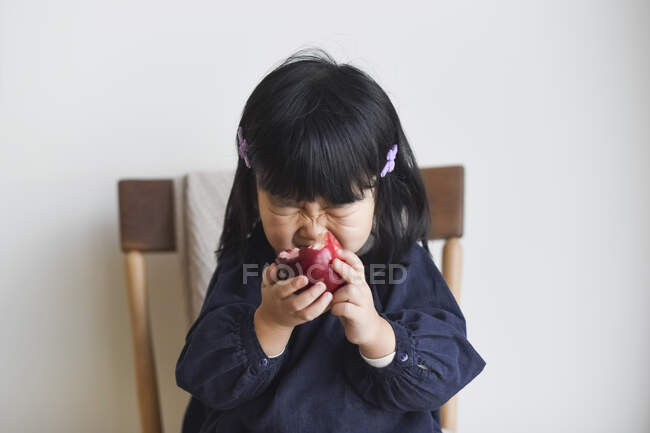 Маленькая девочка кусается в яблоко — стоковое фото