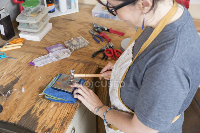 Женщина-ювелир работает с инструментами в мастерской — стоковое фото