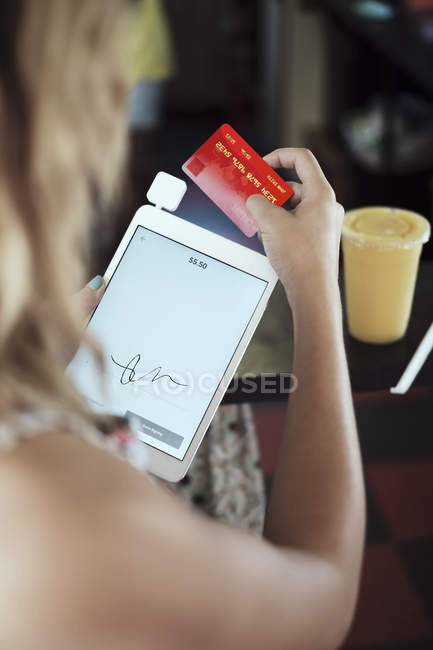 Через плечо вид молодой женщины, держащей цифровой планшет и кредитную карту — стоковое фото