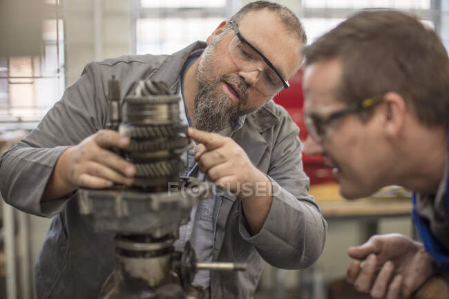 Männliche Automechaniker zeigen auf Autoteil in Werkstatt — Stockfoto