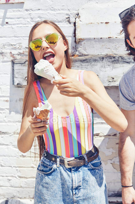 Mujeres jóvenes comiendo helado derretido cono - foto de stock